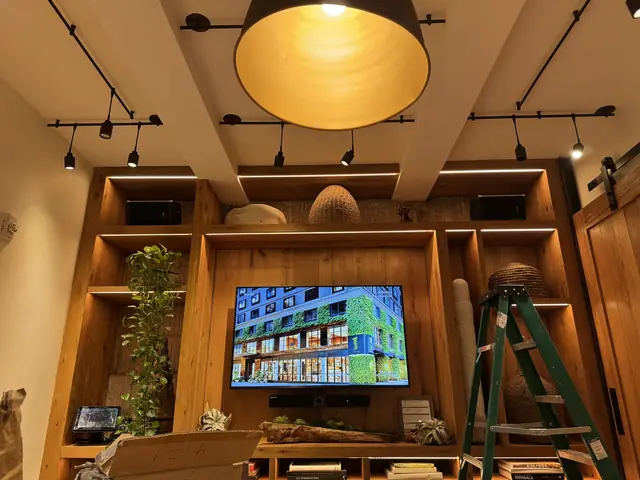 Luces de riel y lámpara colgante sobre un mueble de madera